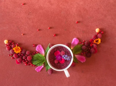 Himbeeren und Blüten in einer Tasse dekorativ platziert