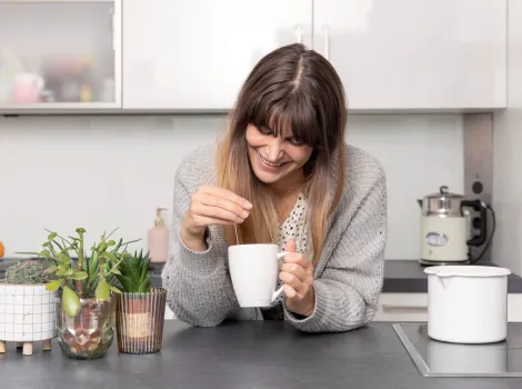 Frau steht mit einer Tasse Tee in der Küche