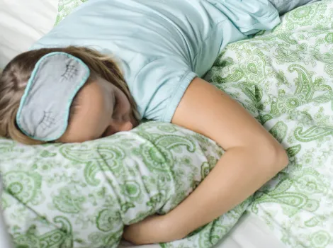 Frau mit Schlafmaske liegt im Bett und schläft