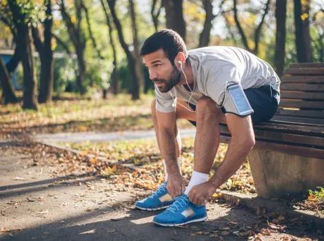 Jogger bindet sich im Park die Schuhe zu