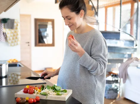 Schwangere Frau schneidet Gemüse