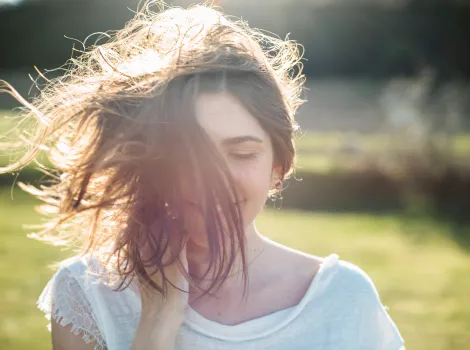 Frau schüttelt ihre Haare in der Sonne