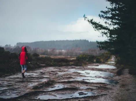 Frau mit roter Jacke geht im Regen