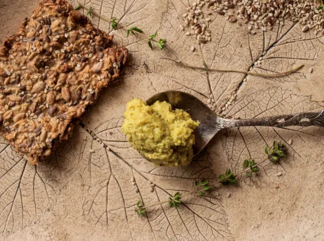 Zucchini Apfel Aufstrich auf einem Löffel und ein Sonnenblumenkernbrot