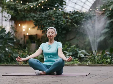 Sport Energie Meditation Yogamatte Schneidersitz mittelalte Frau ältere Frau 60+ 50+ Graues Haar grün blau türkis Garten Augen geschlossen entspannen Alter