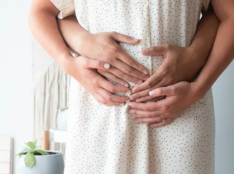 Hände von Frau und Mann halten Schwangerschaftsbauch
