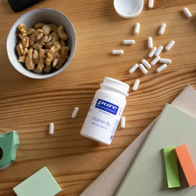 Vitamin B12 auf einem Schreibtisch neben Nüssen