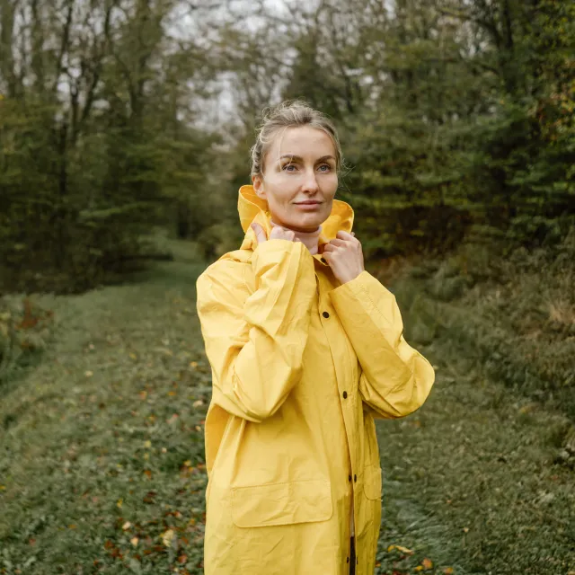 Frau mit Regenmantel im Wald