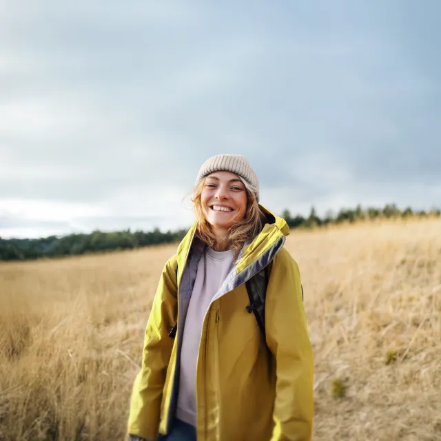 Frau steht in einem herbstlichen Feld