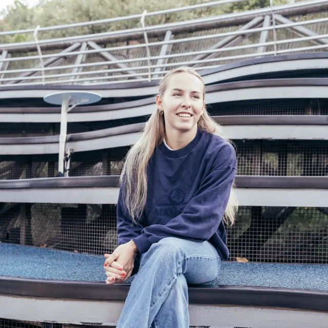 Isabelle Engel sitzt auf einer Tribüne und lächelt