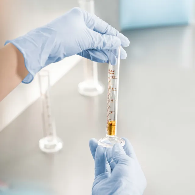Ein Reagenzglas in Händen mit Handschuhen