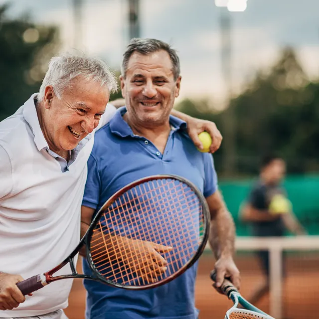 Zwei Männer mit Tennisschlägern lachen