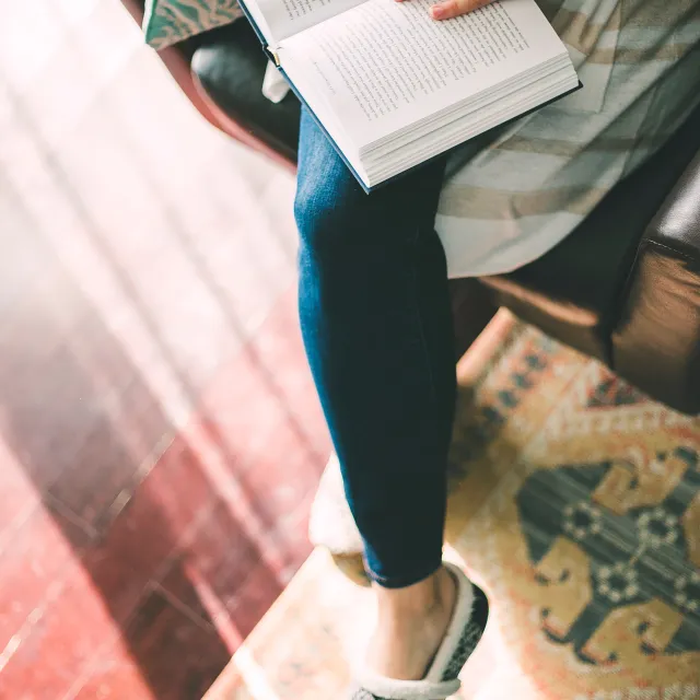 Aufgeschlagenes Buch liegt Frau am Schoß