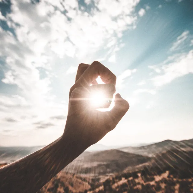 Eine Hand umkreist Sonnenstrahlen