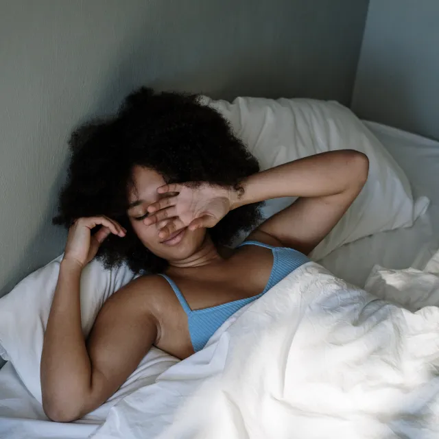 Frau liegt verschlafen im Bett
