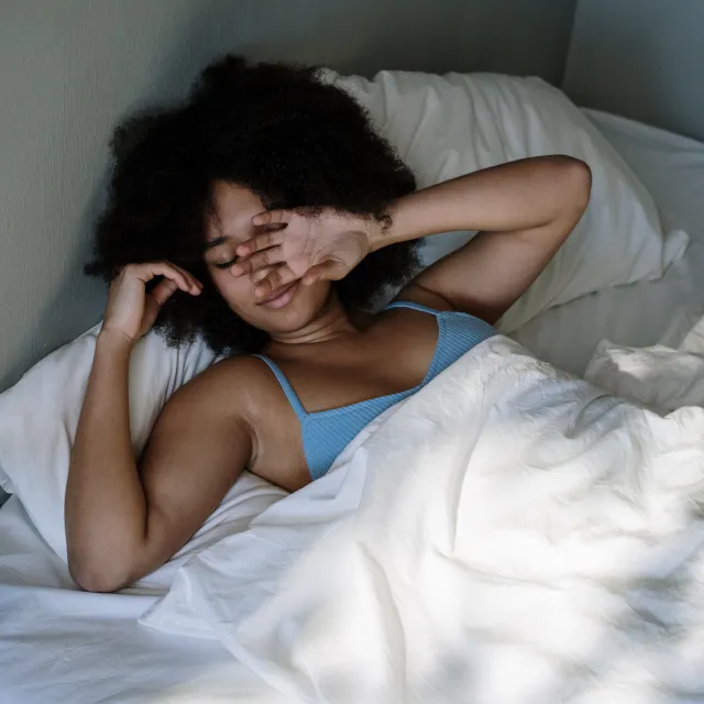 Frau liegt verschlafen im Bett