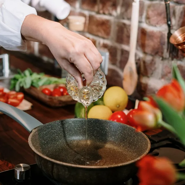 Frau gießt Öl in eine Pfanne und kocht