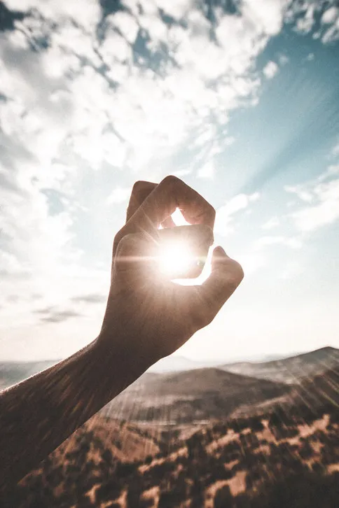 Eine geformte Hand ausgestreckt in Richtung Sonne