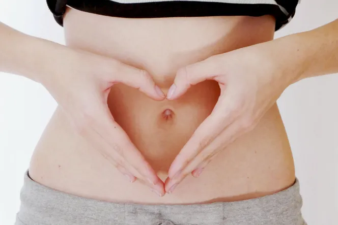 Bauch mit gefaltenen Händen, die ein Herz bilden, davor