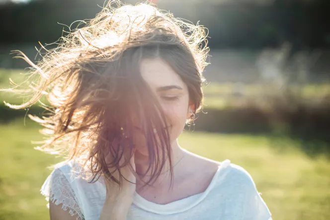 Frau schüttelt ihre Haare in der Sonne