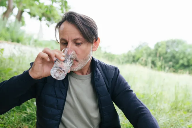 Mann trinkt aus Wasserglas