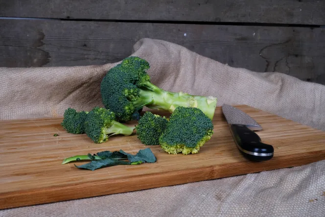 Brokkoli und ein Messer auf einem Holzbrett