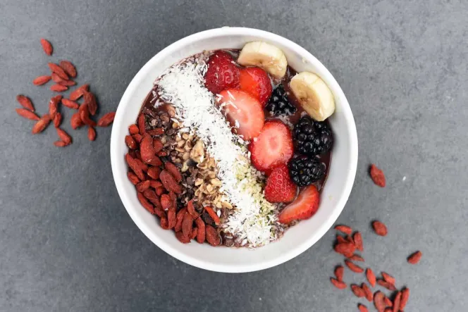 Porridge mit Obst, Kokosraspeln und getrockneten Beeren