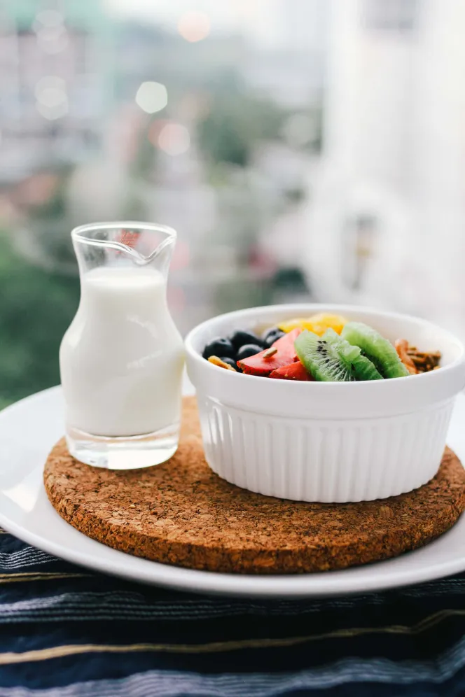 Obst in einer Müslischüssel mit einem Kännchen Milch daneben