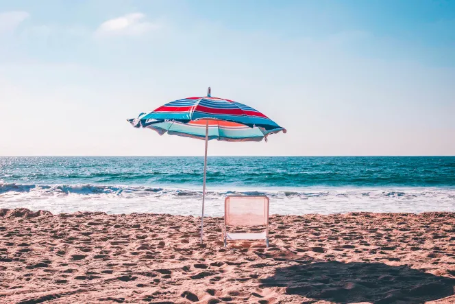 Ein Liegestuhl und ein Sonnenschirm am Strand