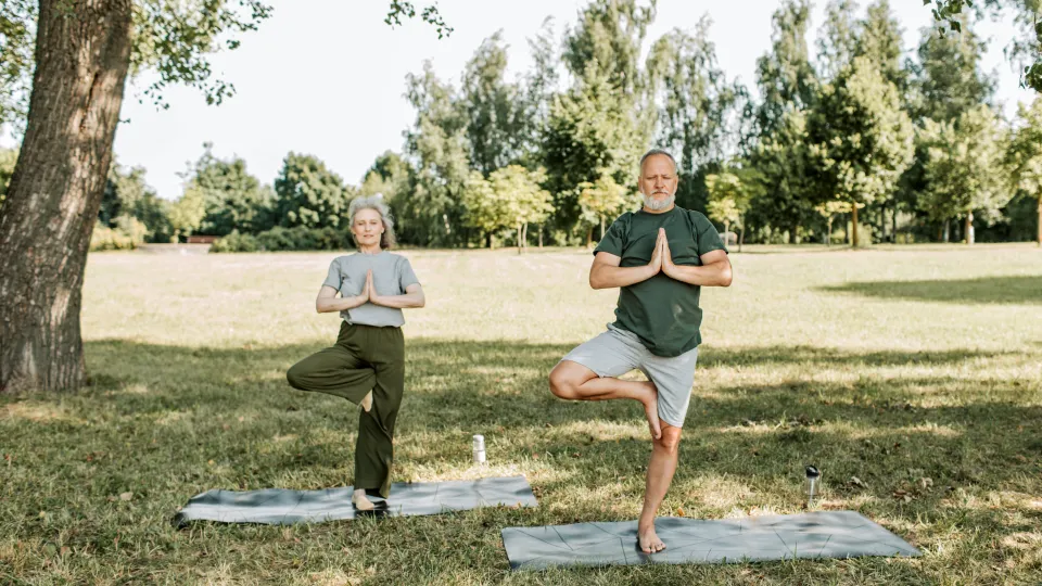 Mann und Frau machen Yoga im Park