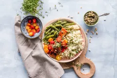 Gefüllter Teller auf Holzbrett mit Spargel, Tomaten Lachs und Quinoa 