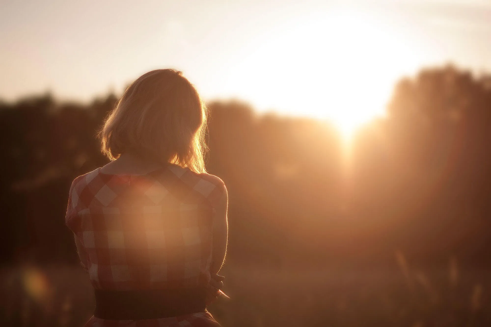 Der Rücken einer Frau in der untergehenden Sonne