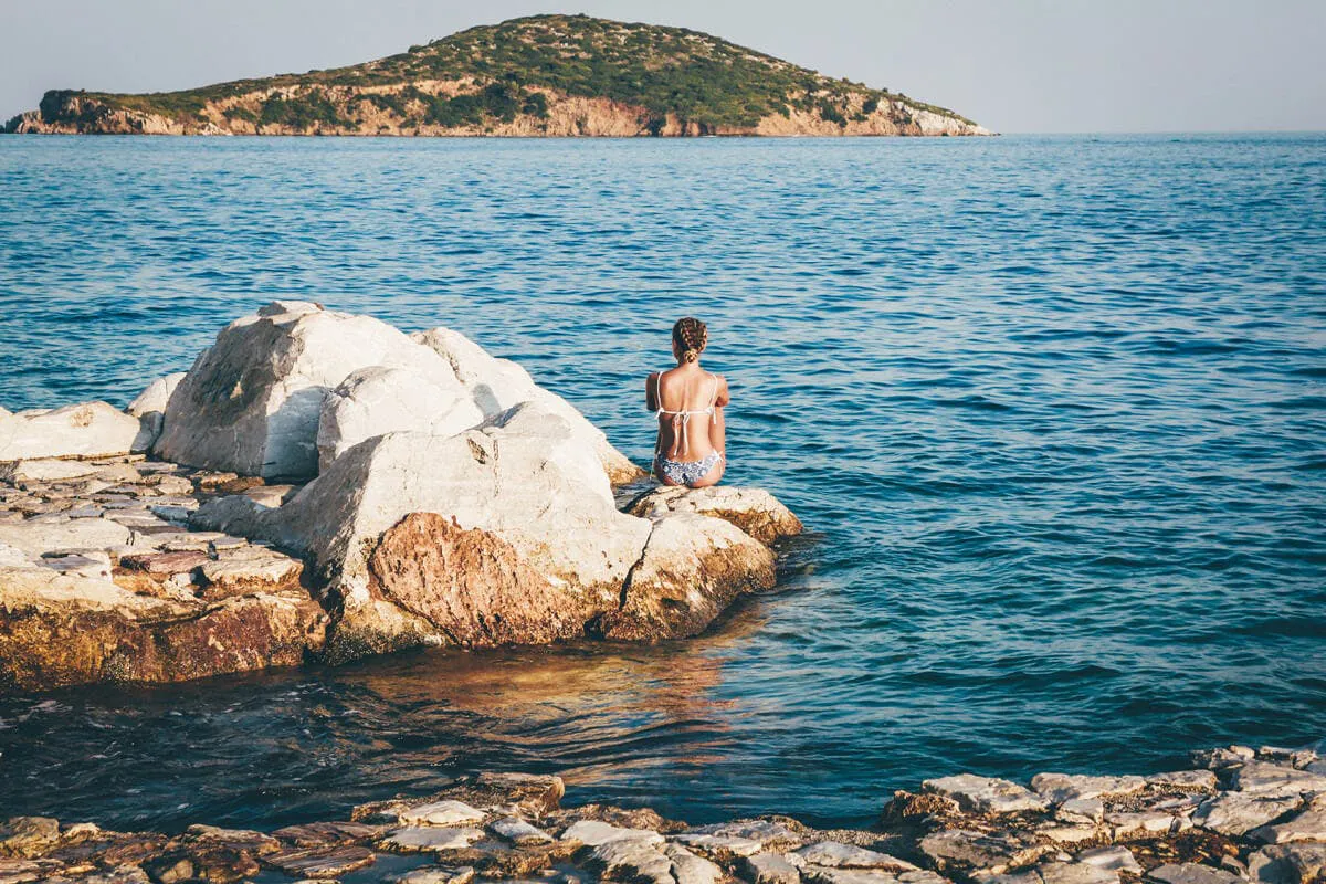 Frau sitzt auf Steinen im Meer