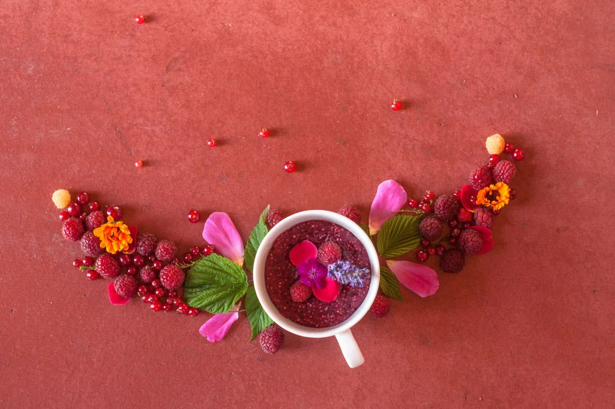 Himbeeren und Blüten in einer Tasse dekorativ platziert