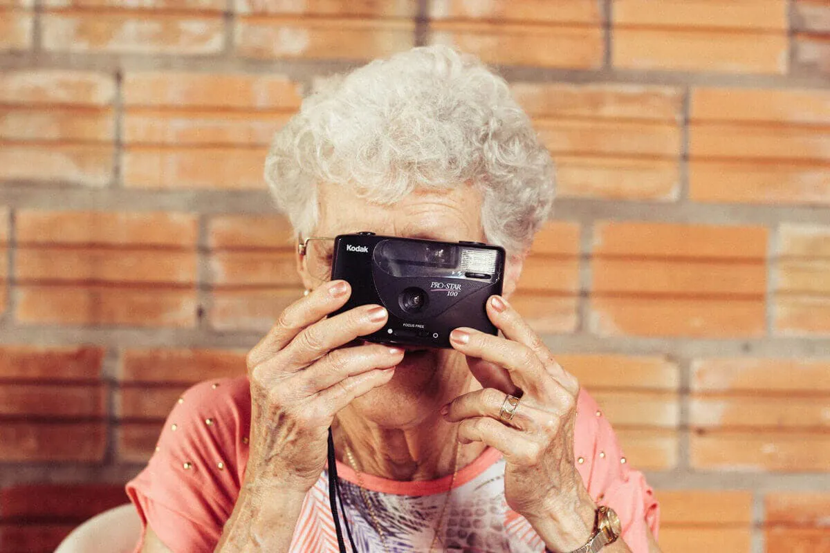alte Frau mit Kamera vor dem Gesicht