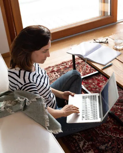 Frau sitzt mit Laptop am Boden