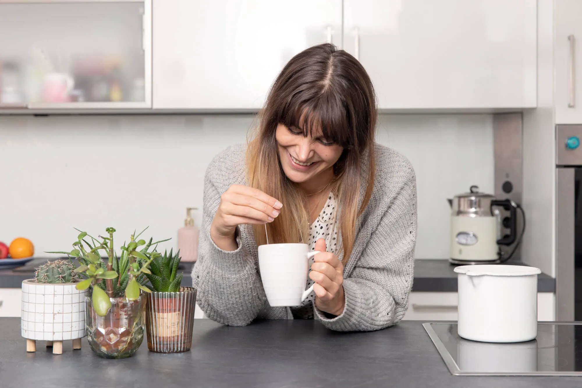 Frau steht mit einer Tasse Tee in der Küche