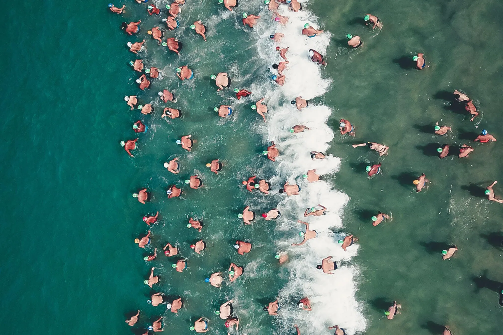 Vogelperspektive von Triathleten beim Start ins Wasser