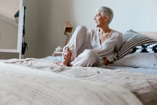 Ältere Frau im Pyjama auf Bett