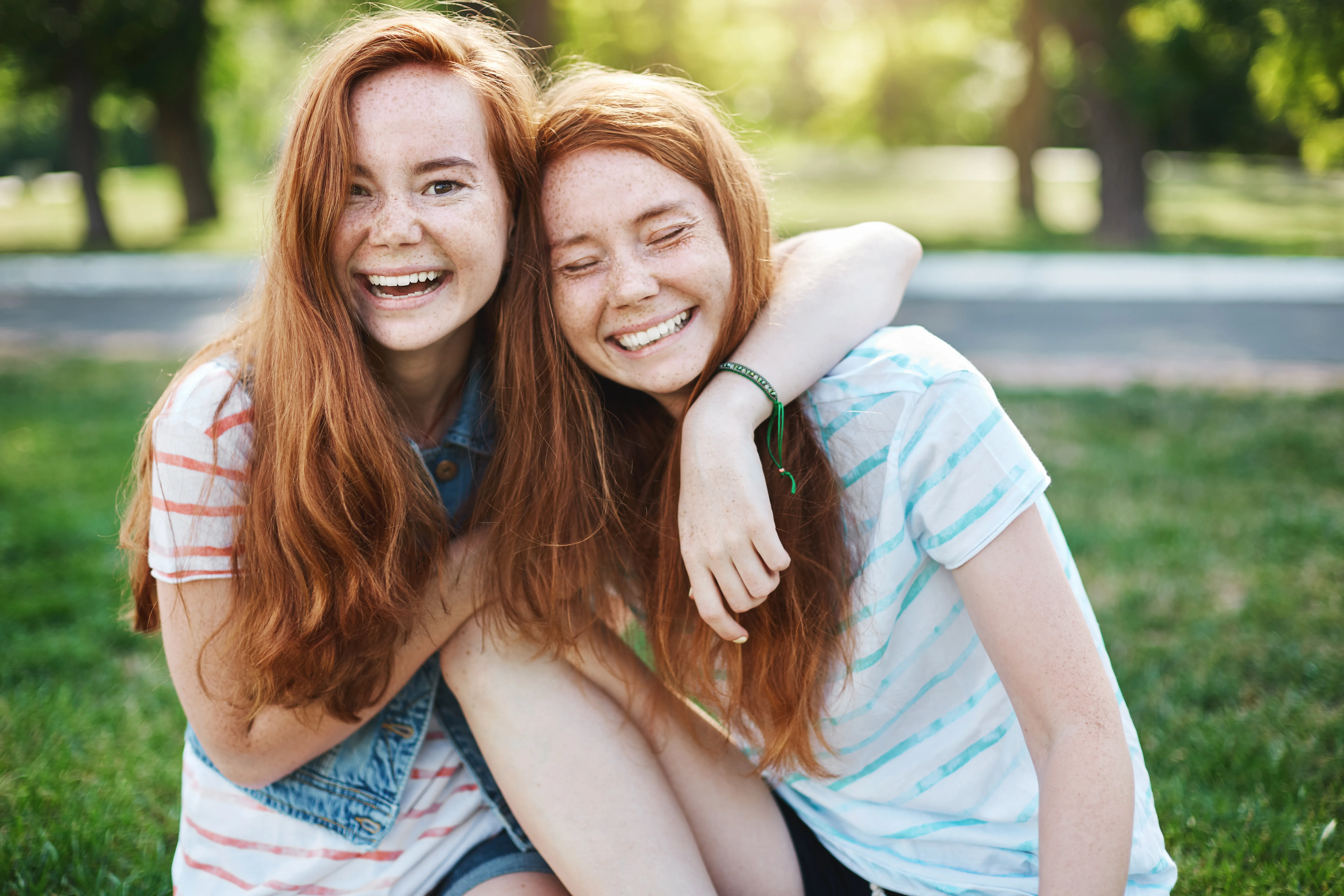 Mädchen jung Zwillinge rothaarig Sommer Frühling lachen umarmen grün AdobeStock 216716942