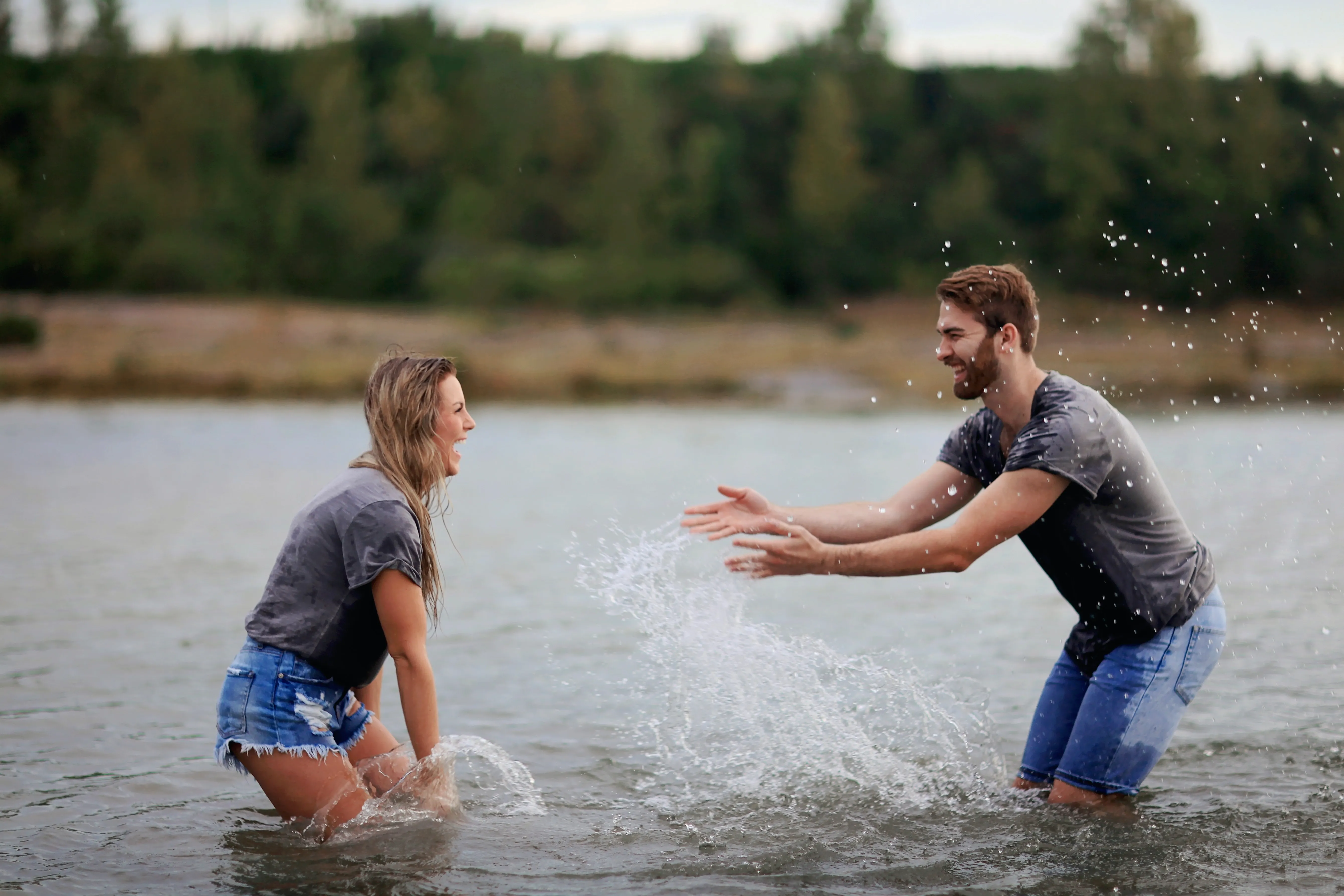 junges Paar Fluss Wasser Sommer grau blau grün Pärchen Spaß Freude lachen glücklich Energie