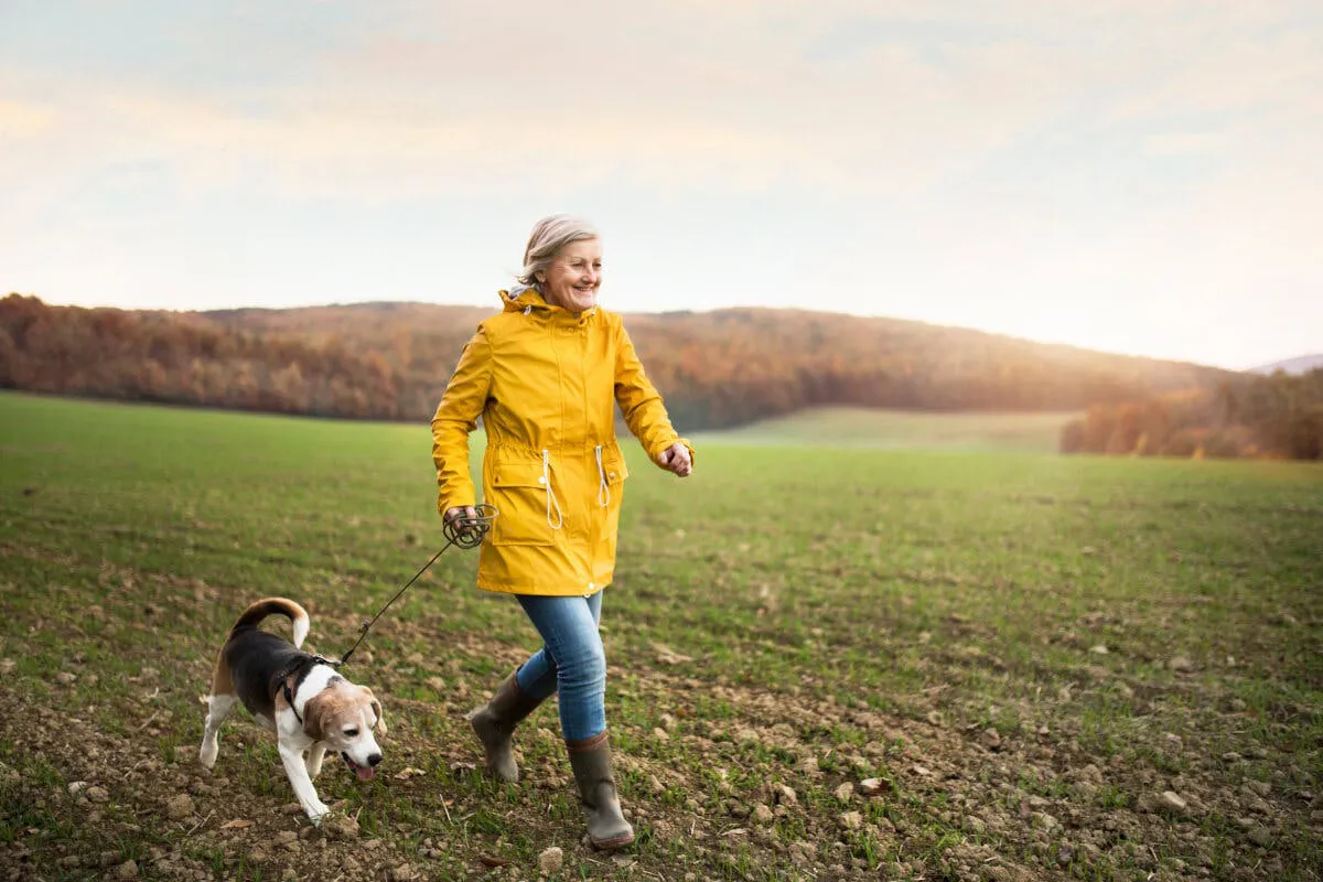 Ältere Frau beim Spazieren mit Hund