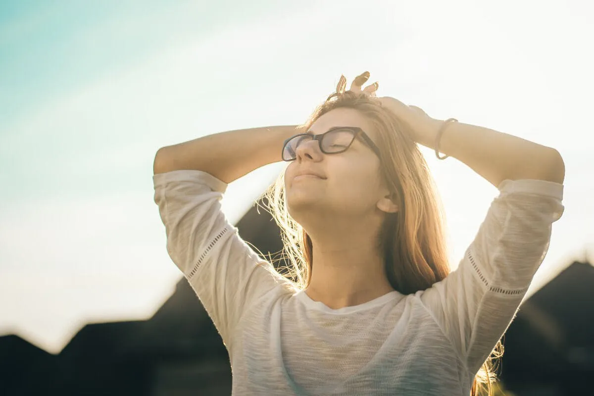 Frau mit Brille lässt sich von Sonne anstrahlen