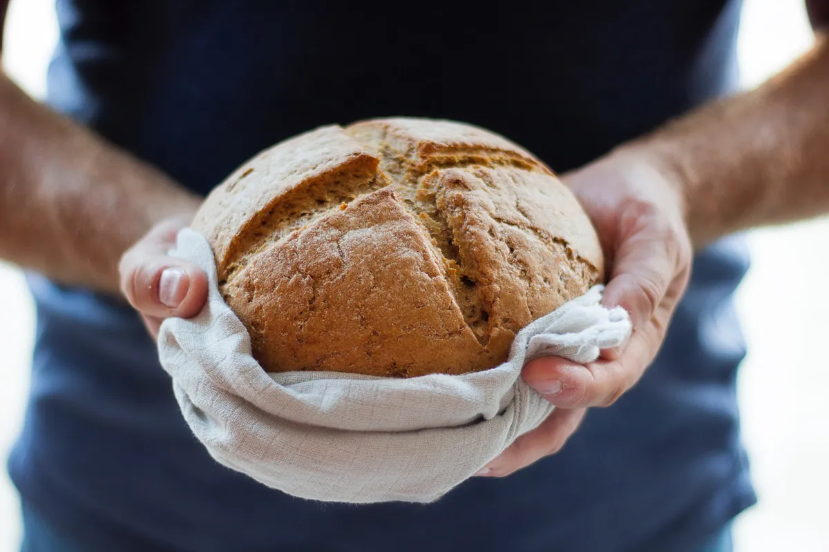 Mann hält frischen Brotlaib in einem Tuch