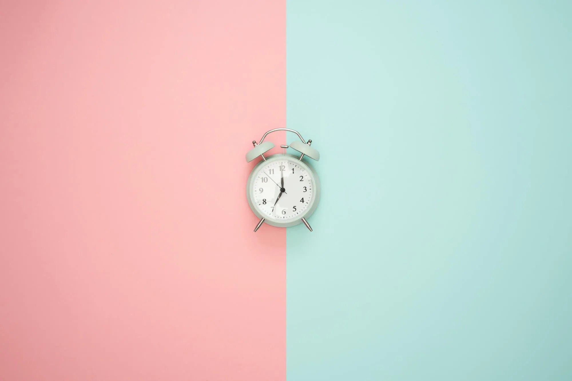Eine Uhr vor einen rosa und grünen Hintergrund 