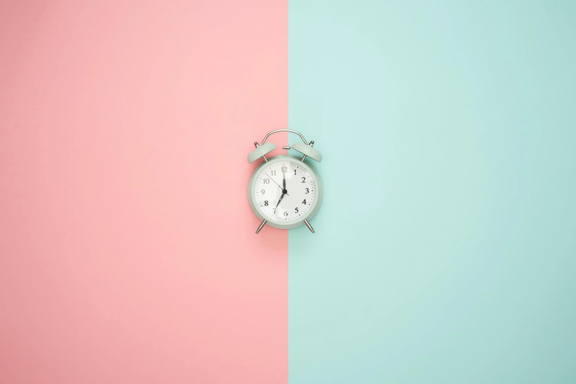 Eine Uhr vor einen rosa und grünen Hintergrund