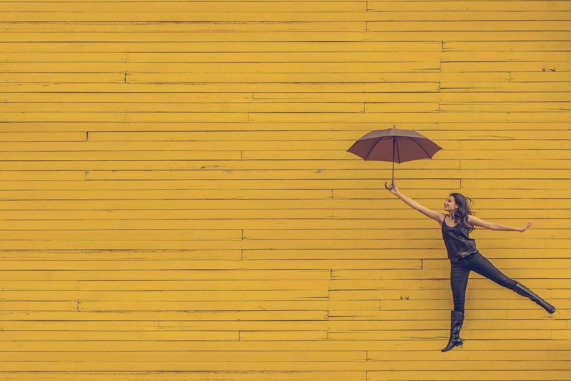 Frau springt mit Regenschirm in der Hand