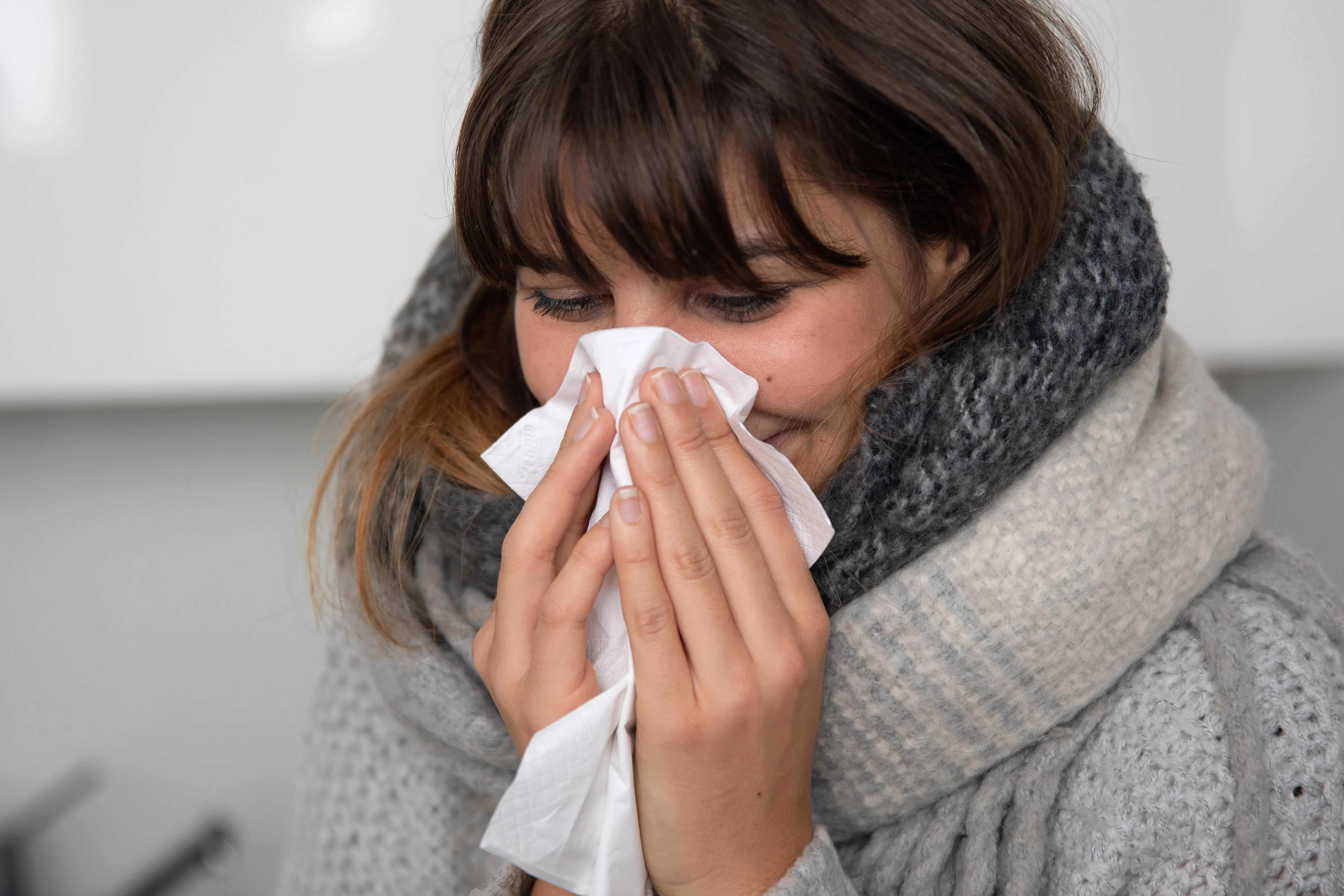 Frau schnäuzt sich. Grippe oder grippaler Infekt?