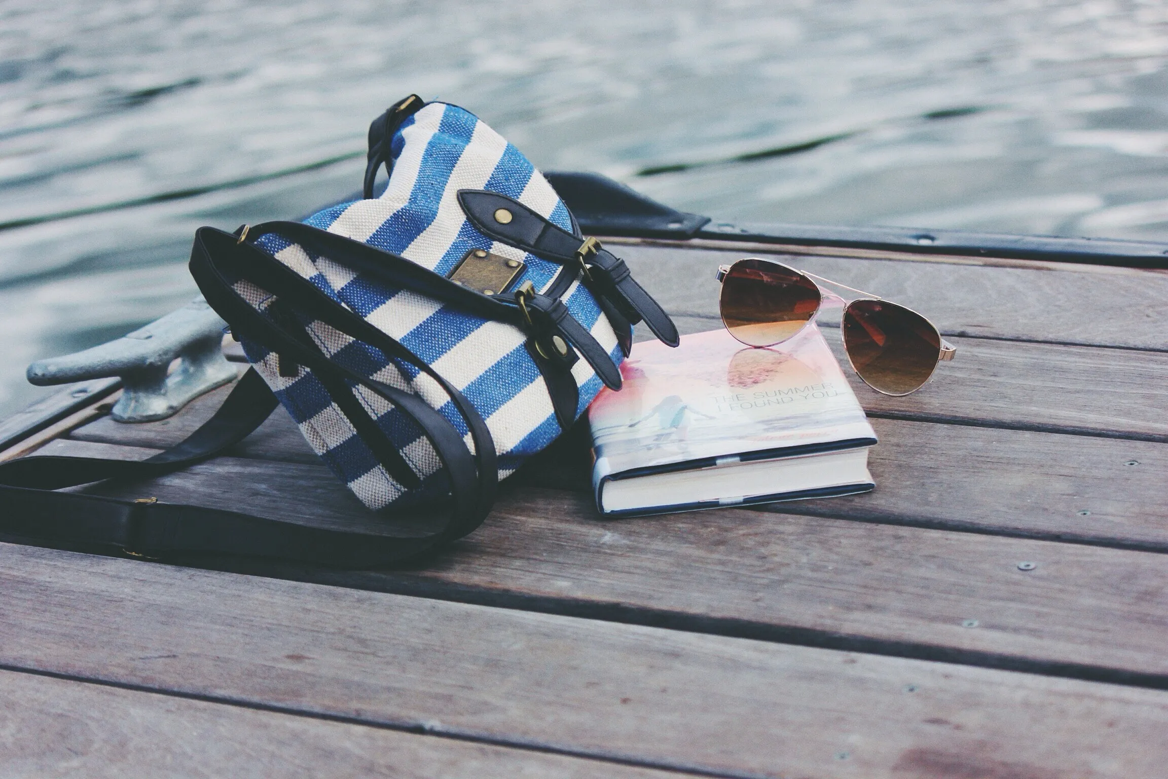 Tasche, Buch und Sonnenbrille auf einem Steg