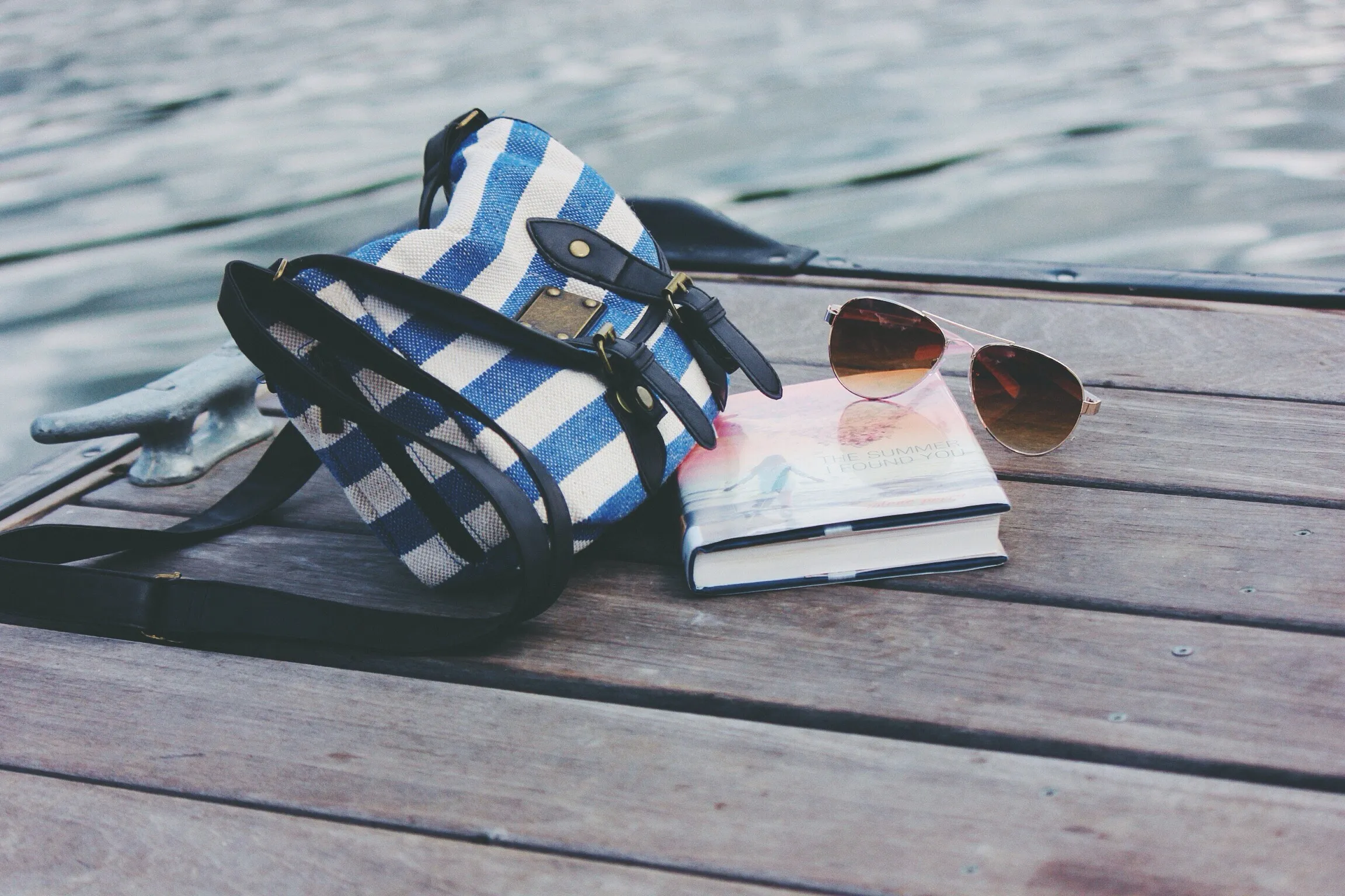 Tasche, Buch und Sonnenbrille auf einem Steg